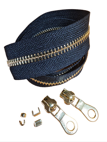 A yard of YKK EVERBRIGHT zipper in brass and black, displayed alongside zipper sliders and other components, against a white background.