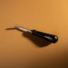 A stainless steel roughing tool used for texturing leather textiles and projects. Laid out on a light brown textured leather background.