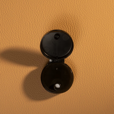 Black Plastic lid for a dye cap, laid out on a brown textured leather background.