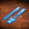 A set of acrylic blue templates used for creating a custom pair of suspenders out of leather. Laid out on a textured brown leather background.