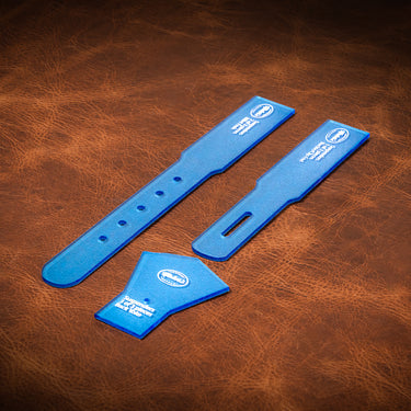 A set of acrylic blue templates used for creating a custom pair of suspenders out of leather. Laid out on a textured brown leather background.