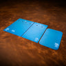 a set of acrylic blue templates used for creating a custom drawstring bag made from leather. Laid out on a textured brown leather background.