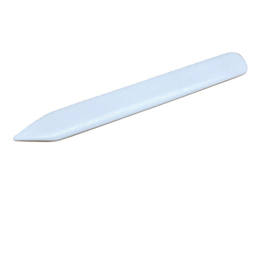 A white bone folder placed on a smooth white background.