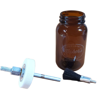 A 5oz amber-colored glass glue jar labeled with 'Maker's Leather Supply' with a brush connected to the cap, placed on a white background