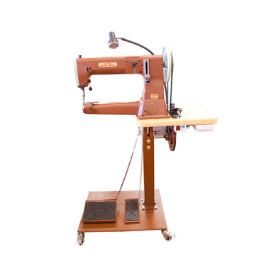 A brown Cobra Class 4 sewing machine on a pedestal stand with locking casters, equipped with a sewing lamp and various machine parts visible.