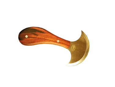 A small round knife with a wooden handle and a curved steel blade, placed on a green cutting mat.