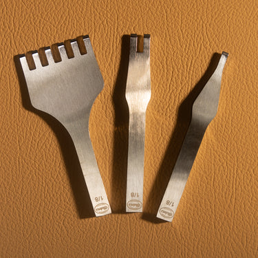 A set of 3 buck-stitching chisels used for stitching with leather projects in the small size. Laid out on a light brown textured leather background. 