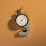 A leather gauge tool used for determining the thickness of a leather textile, laid out on a textured brown leather background. 
