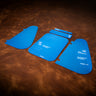 A set of blue acrylic templates used for creating a custom pistol case made of leather. Laid out on a textured brown leather background. 