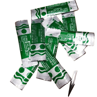 A collection of scalpel blades with green and white packaging, some blades are still in their individual packaging while others are loose.